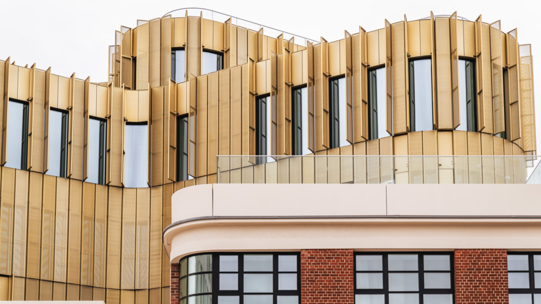 The project preserves the 1935 art deco façade, with its elegant white glazed bricks, while introducing a striking golden office tower behind it ©-PC3_Igor-Sinicins